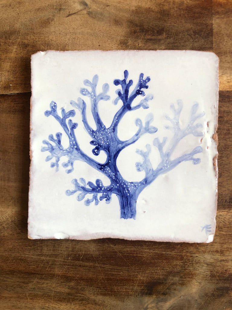 Square tile with blue coral design on a wooden surface. Azulejo portuguese. Kézműves fali csempe.