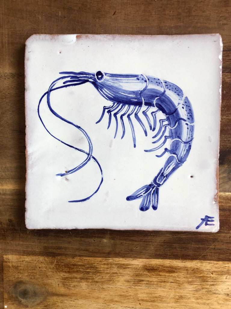 Blue shrimp illustration on a white tile with a wooden background
